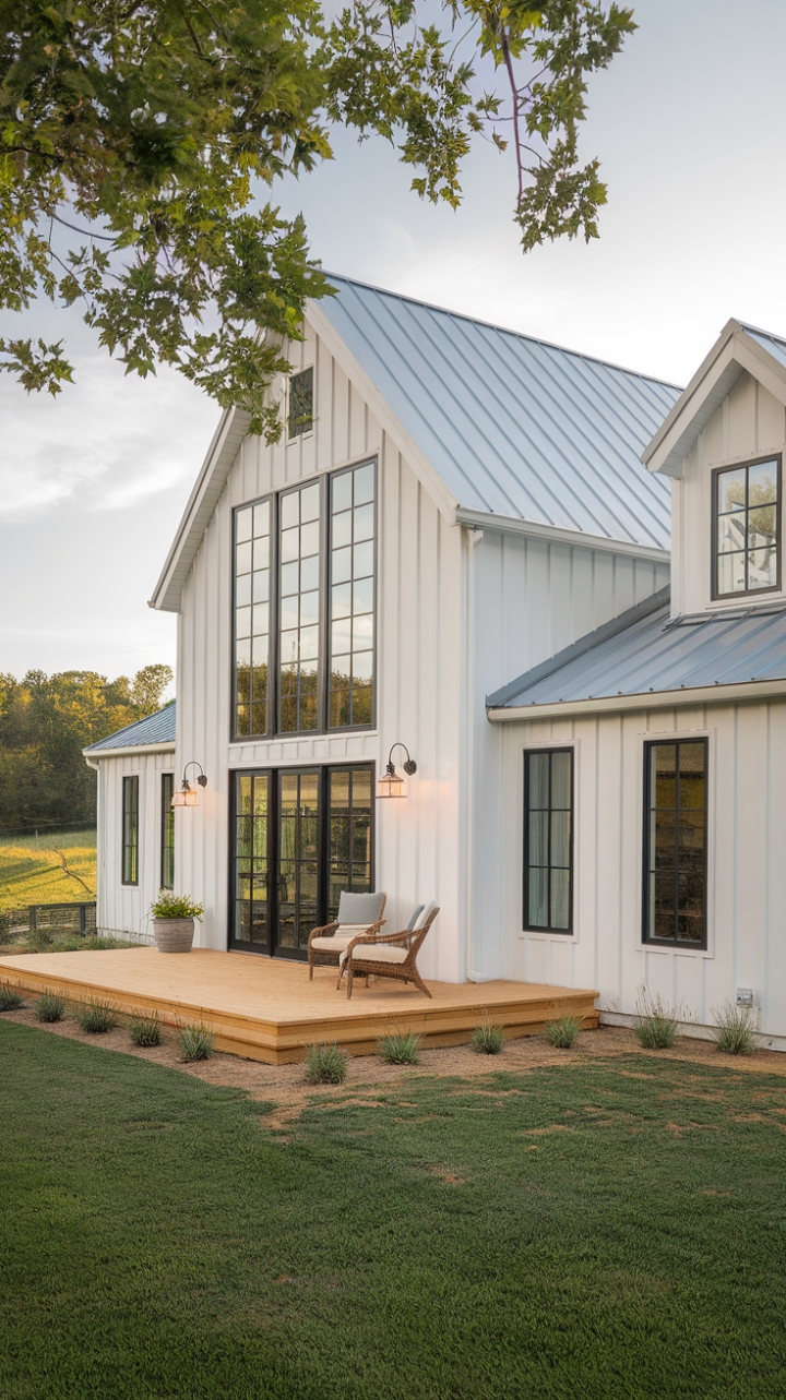 This stunning contemporary farmhouse exudes modern rustic charm, featuring a crisp white exterior accented by bold black trim that creates a striking contrast. Large windows invite natural light to flood the interior, while the sleek metal roof adds a touch of industrial flair. A welcoming wooden deck adorned with stylish chairs beckons you to unwind and soak in the serene surroundings, where a lush green landscape and towering trees provide a picturesque backdrop that enhances the home’s tranquil ambiance.