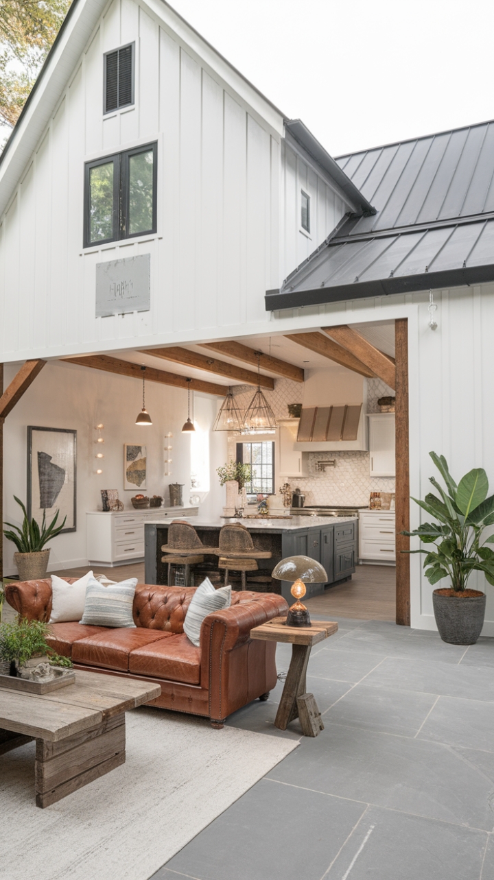 This contemporary farmhouse beautifully marries modern aesthetics with rustic charm, showcasing a striking white exterior complemented by bold black accents and a sleek metal roof. Inside, the minimalist design shines through, featuring a spacious kitchen anchored by a large island, exposed wooden beams that add warmth, and a rustic dining table that invites gatherings. The living room exudes comfort with a sumptuous leather sofa, a handcrafted wooden coffee table, and a vintage lamp that casts a cozy glow. Lush potted plants and curated artwork adorn the walls, while the expansive gray tile flooring grounds the space in understated elegance.